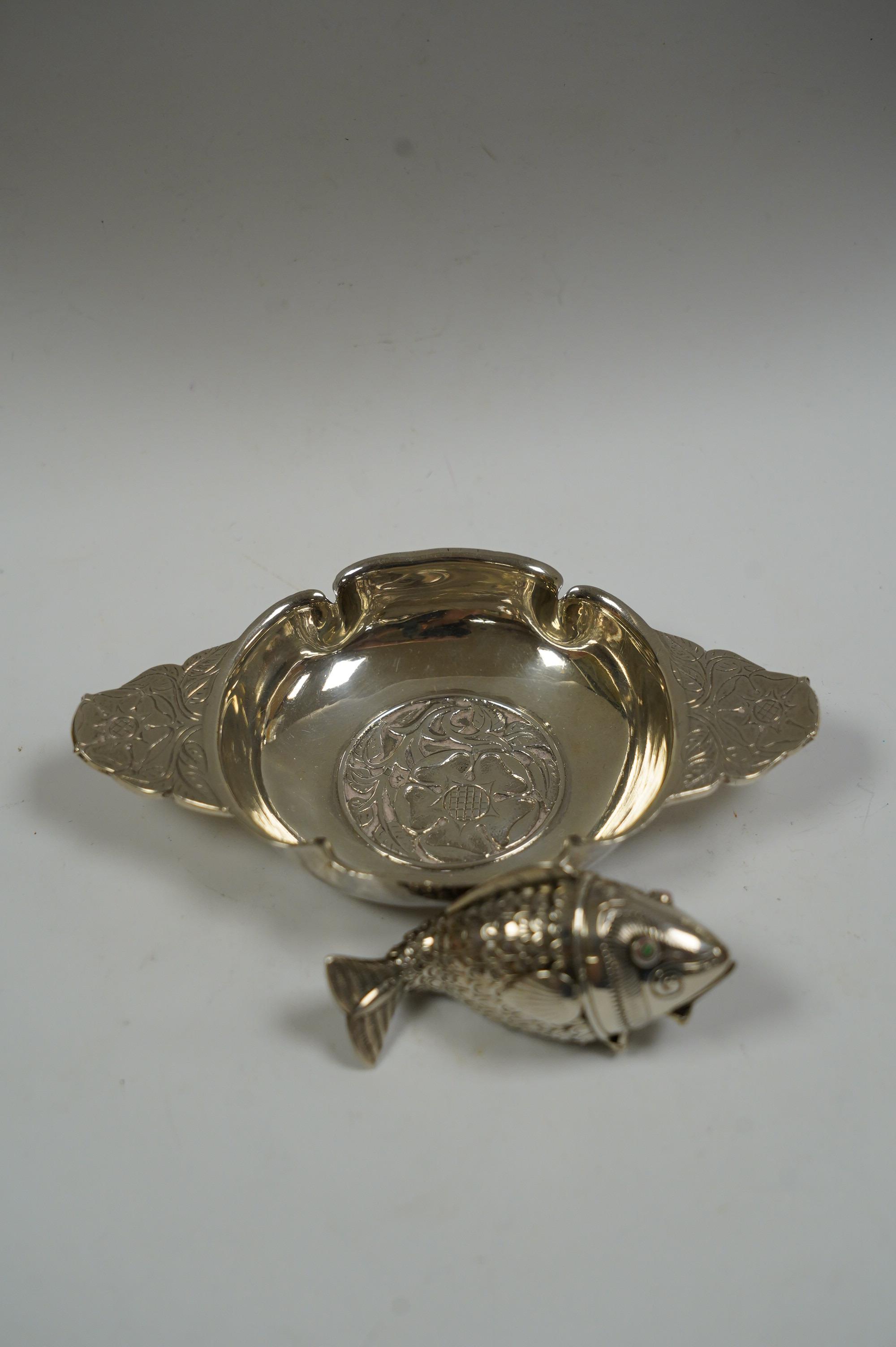 A George V foliate engraved silver quaich by Robert Edgar Stone, London, 1936, 12.2cm, together with a Norwegian 830 standard white metal articulated fish pill box, 60mm. Condition - fair to good